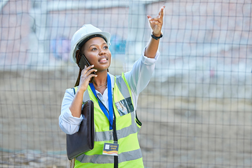 Engineer, construction worker or maintenance and development woman on a phone call while working. Building management employee or manager planning and consulting real estate building project outdoors