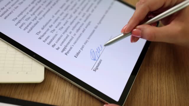 Woman hand holding stylus puts digital signature on document closeup