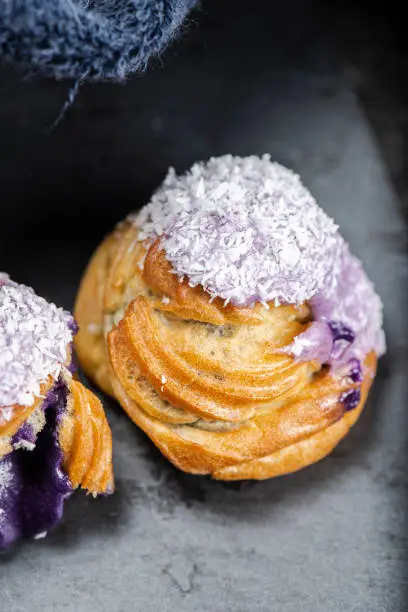 Home made ube cream puff with purple coloured white chocolate and coconut, also known as a Profiterole.