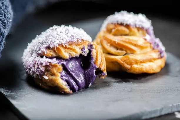 Home made ube cream puff with purple coloured white chocolate and coconut, also known as a Profiterole.