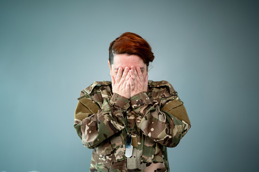 Female soldier covering face with hands