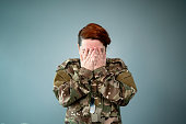 Female soldier covering face with hands on a studio shot