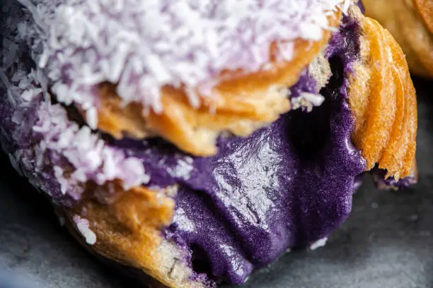 Home made ube cream puff with purple coloured white chocolate and coconut, also known as a Profiterole.