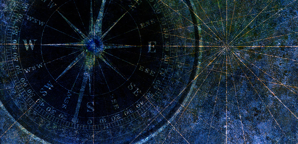 A compass on a map with navigational lines on a dark blue background.