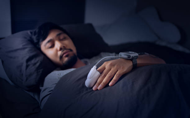 hombre que usa un oxímetro de pulso - prueba de estudio del sueño en el hogar para la apnea del sueño - apnea del sueño fotografías e imágenes de stock