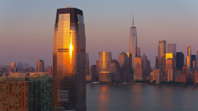 Downtown Manhattan distant view over the Hudson River from Paulus Hook in Jersey City at sunset. Aerial video with the panning camera motion.