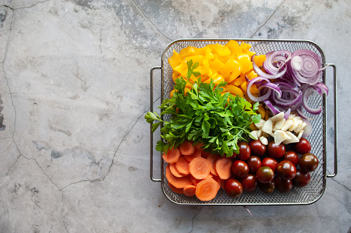 Vegetables on a plate, yellow peppers, onions, carrots and cherry tomatoes, top view, space for text