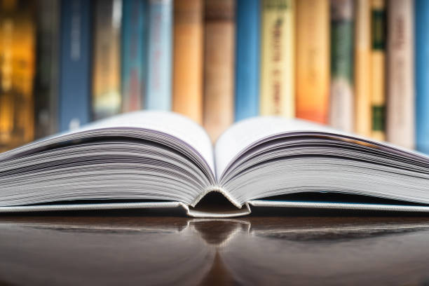 istock Closeup of opened  book with blurred library shelf 1430896328