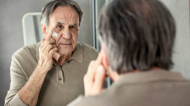 istock Old man applying cream to his face 1430896396