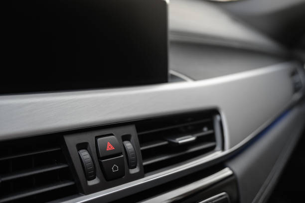 Close up of a modern car center console with brushed aluminum trim.  Focus on hazard light and infotainment home buttons.