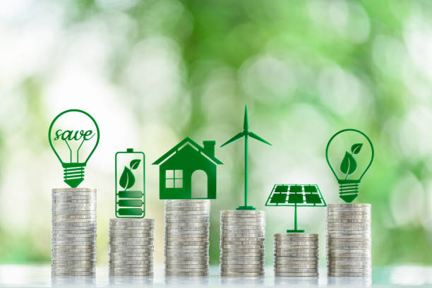 再生可能エネルギーまたはクリーンエネルギー発電の価格とコスト、財務コンセプト:エネルギー効率の高い電球、バッテリー、太陽電池パネル、風力タービンなどのコインスタックの上にあ - 電球形蛍光灯 ストックフォトと画像