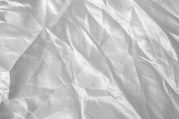 istock White crumpled satin fabric, abstract background close up 1430907434
