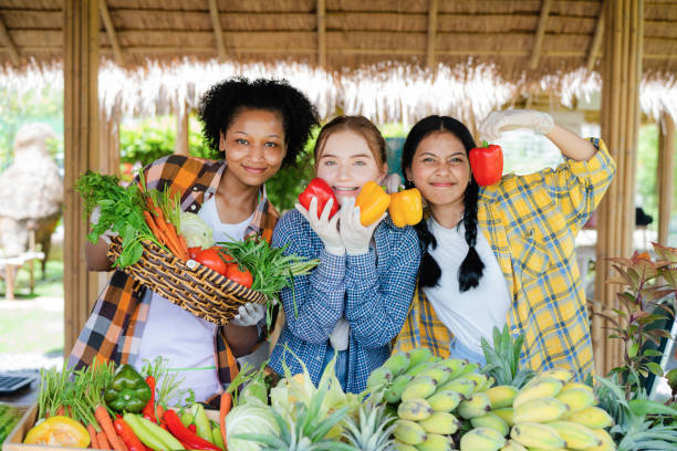 Smiling teenage holding vegetables on fruit stall stock photo