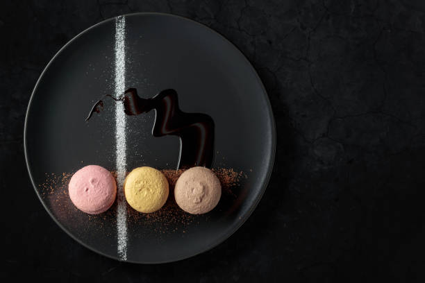 istock Macaroons on a black plate garnished with chocolate sauce and cocoa powder. 1430910630