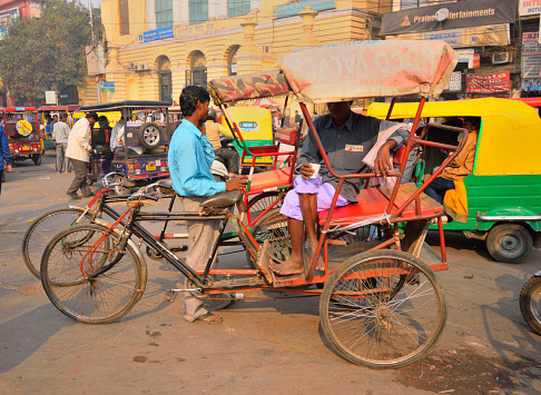 Delhi, India - November 20, 2017: A rickshaw puller waiting for passengers in the road.