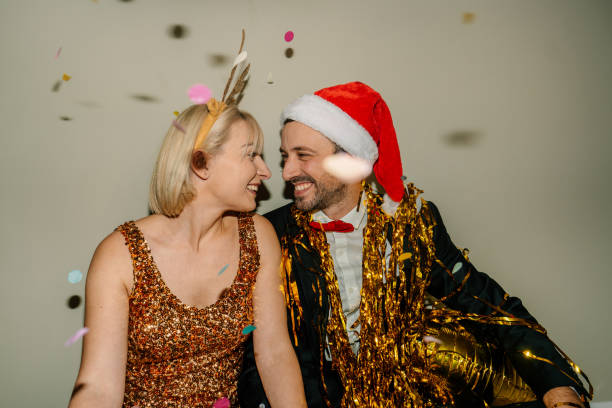 Photo of a smiling couple celebrating New Year's Eve, while colourful confetti falling over during countdown