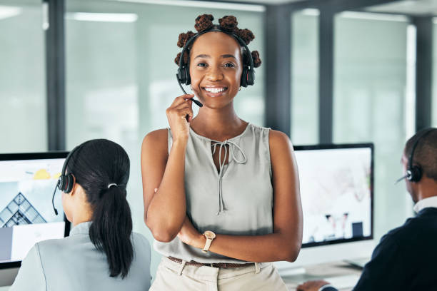 call center agent leader standing with arms crossed, looking proud and wearing a headset in an office with colleagues. portrait of a smiling female customer service working looking confident - women customer service representative service standing imagens e fotografias de stock