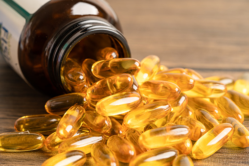 Fish oil Omega 3 capsules vitamin with EPA and DHA isolated on wooden background.
