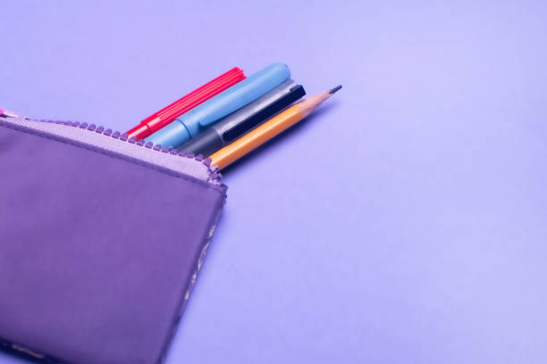 модный фиолетовый пенал с разноцветными фломастерами, карандашами и ручками на сиреневом фоне. - hued стоковые фото и изображения