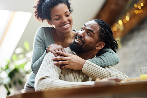 Happy African American couple communicating while enjoying in dining room. Focus is on man.