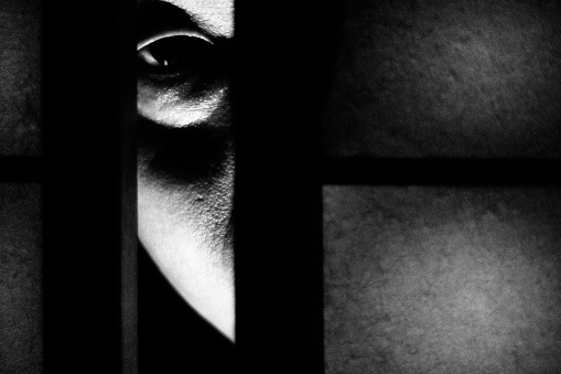 A close-up of a person's eye peeking through a shoji screen