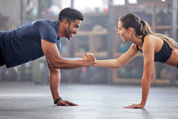 istock Support, teamwork and fitness couple doing workout training, challenging exercise for endurance, strength and stamina in a gym. Active, fit man and woman giving support and motivation during pushup 1430938364