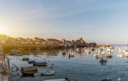 wide panoramic view on beautiful french village Barfleur at the Normandy coast at sunset hour with anchored vessels in the port