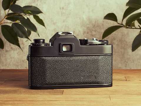Professional vintage SLR analog 35mm film camera on wooden table