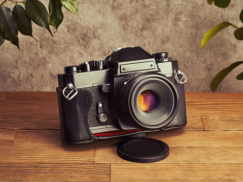 Professional vintage SLR analog 35mm film camera on wooden table