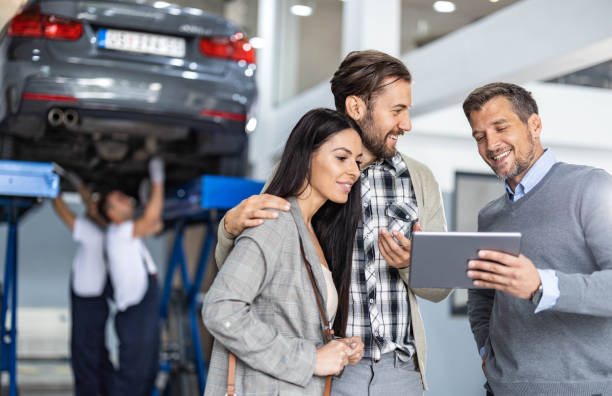 feliz gerente y joven pareja usando touchpad en taller de reparación de automóviles. - auto repair shop mechanic digital tablet customer fotografías e imágenes de stock