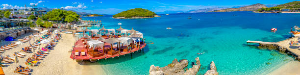 leisure platform under crystal clear waters with an islet in the background of the paradisiacal beach of Ksamil in Albania. stock photo