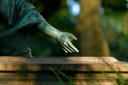 Hand of an old Jesus Christ statue in a cemetery