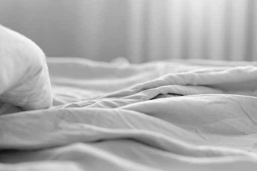 view of the morning crumpled bed in the hotel room. in the morning light. Cozy morning atmosphere.\n unmade bedding for sleeping. Shallow depth of field. Selective focus. color 2022