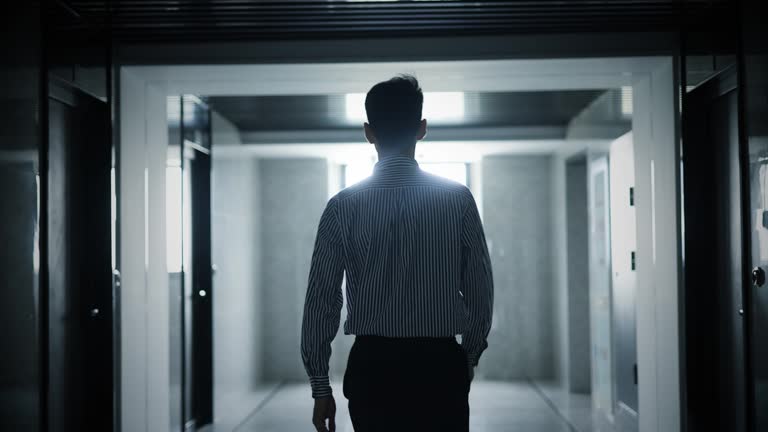 Businessman walking along the dark corridor