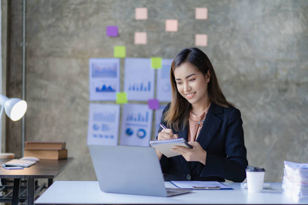 istock Asian businesswoman with chart or document at work using business laptop calculator financial accountant calculating money 1430951954