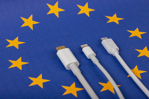Concept for EU law to force USB-C chargers for all phones. EUROPEAN UNION flag and USBC universal charging cable as a standard for small electronic devices