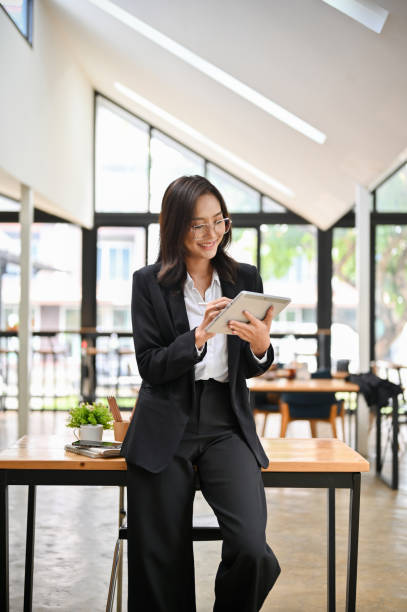 istock Successful Asian businesswoman leaning on the table, using her digital tablet. 1430957713