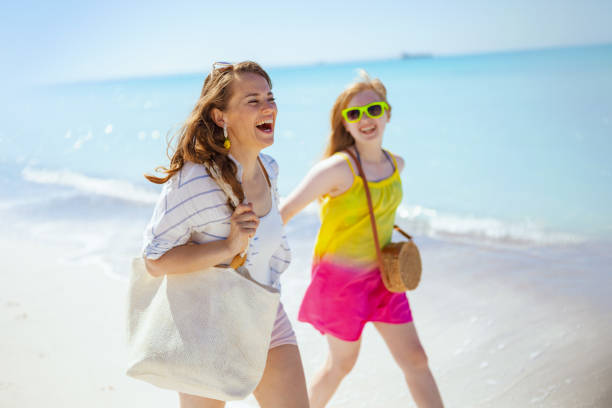 улыбающиеся современные мать и ребенок на прогулке по пляжу - teenager parent beach contemporary стоковые фото и изображения