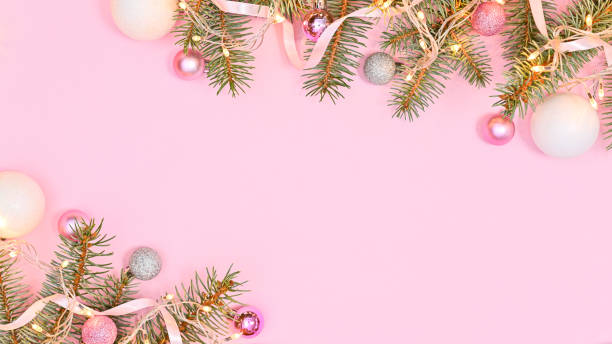 istock Pink background with copy space and silver pine branches decorated with lights and pink and white ornaments. Flat lay 1430958516