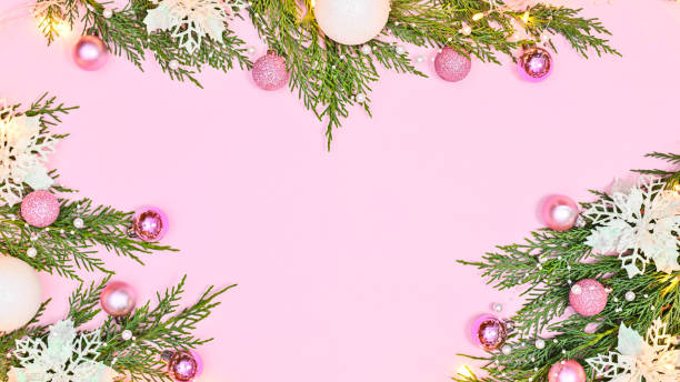 istock Pastel pink background with copy space and pine branches decorated with white flowers and pink ornaments. Flat lay 1430959148