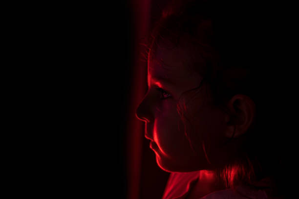 istock sad child girl on a black background with red backlight 1430960911