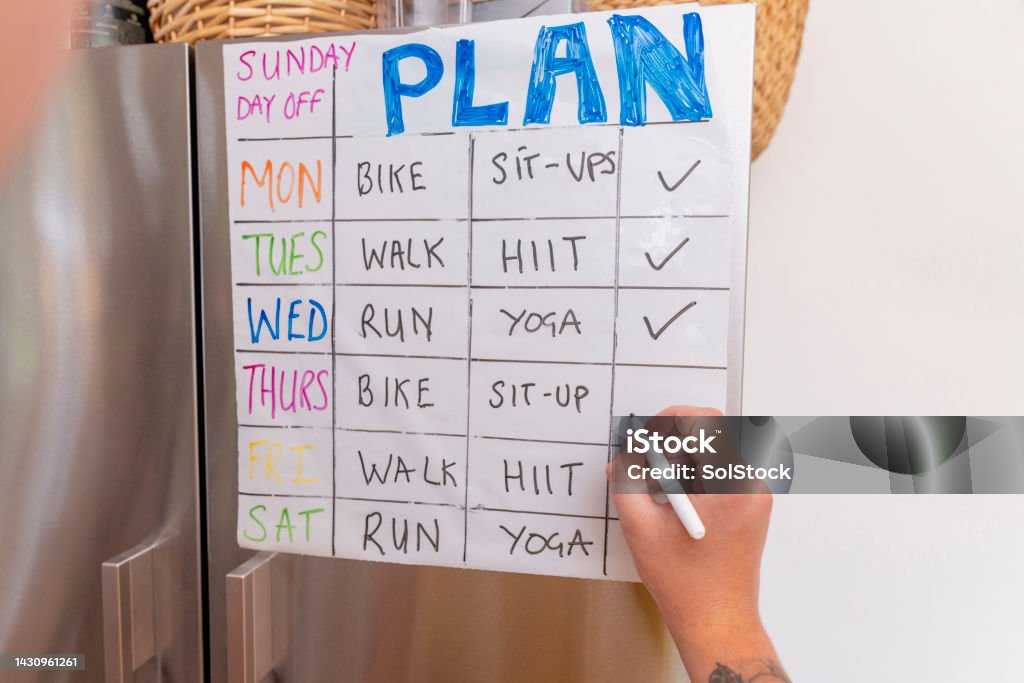 Exercises for the Week Close up of a fitness plan stuck on a refrigerator in the North East of England. An unrecognisable person is checking of their daily fitness activity. Exercising Stock Photo