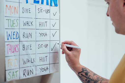 Close up of a fitness plan stuck on a refrigerator in the North East of England. An unrecognisable person is checking of their daily fitness activity.