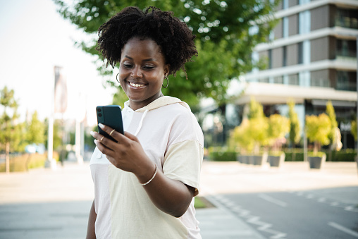 Portrait of a young African American woman enjoying outdoors and using her smartphone