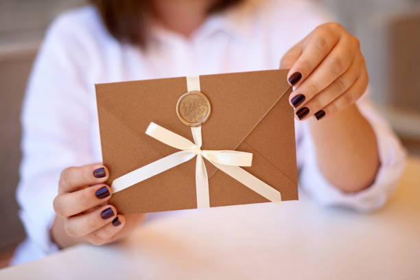 istock woman hands holding bronze invitation envelope with wax seal, gift certificate, present card, wedding invitation 1430966447