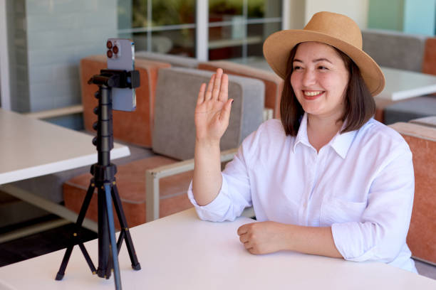 istock caucasian woman in straw hat work or study online with mobile phone on tripod to live streaming in summer terrace cafe 1430966449