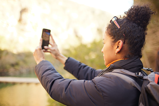 An over-the-shoulder view of a woman taking a photo with a smartphone.