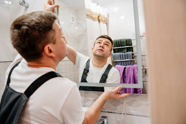 repairman hangs a modern electronic bathroom mirror.
