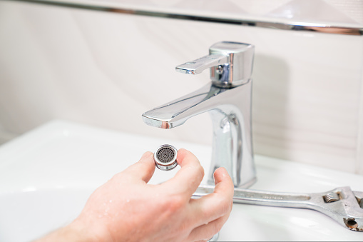 the repairman removes and cleans the Aerator from water stone and rust. special nozzle on the spout spout of the mixer from several strainers.