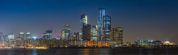 The skyscrapers of Yeouido glittering in the neon night of downtown Seoul across the Han River in the heart of South Korea’s vibrant capital city.
